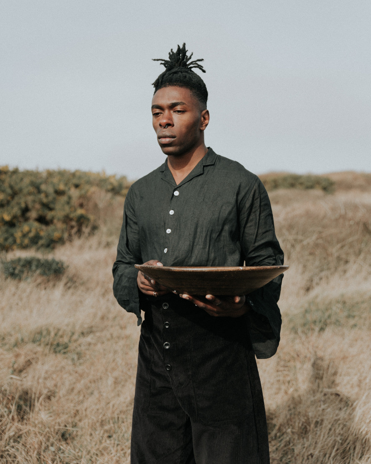 Man holding a bowl in a field with a plain background