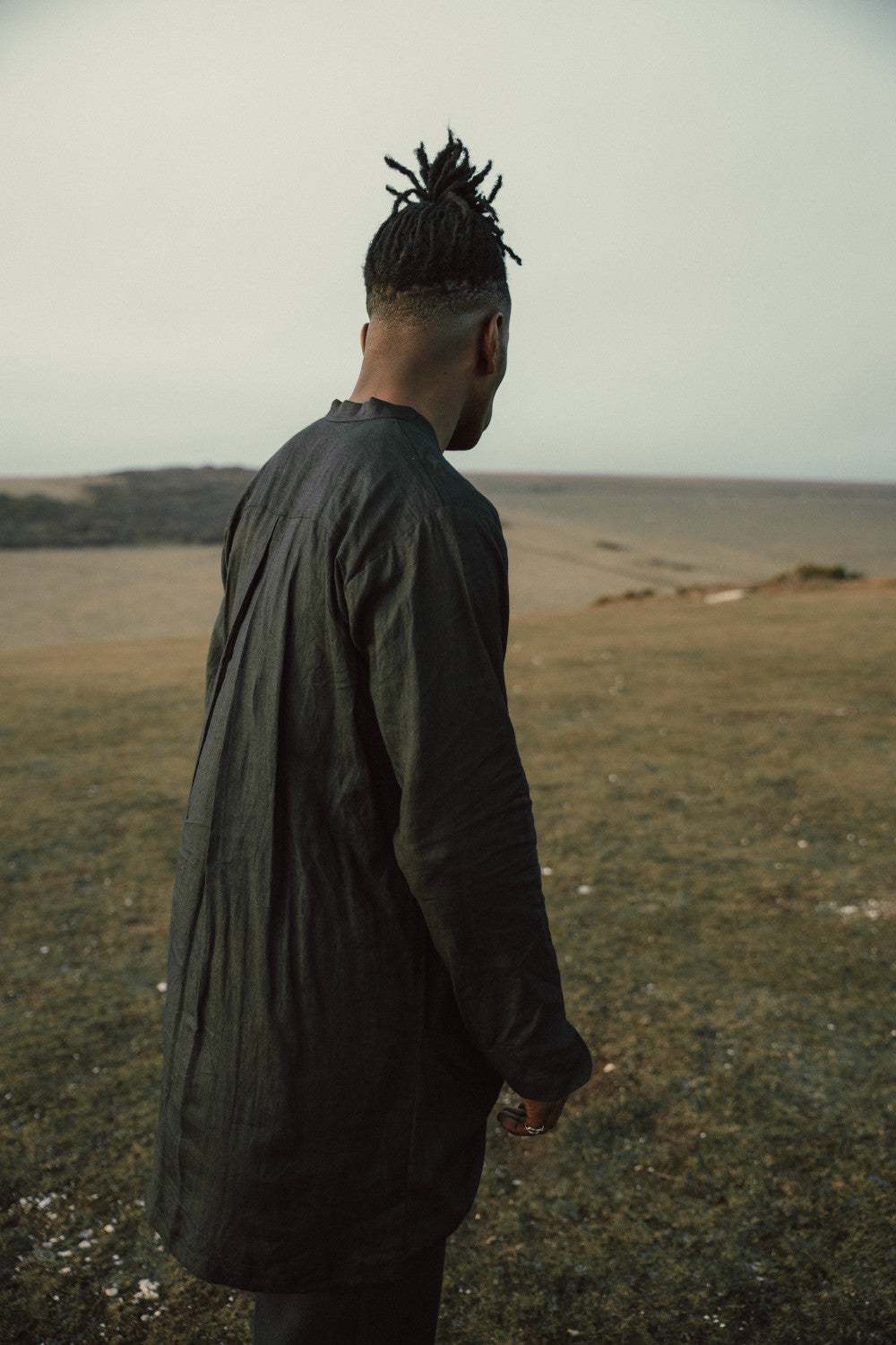 Person wearing a black long shirt standing in a field with a plain background