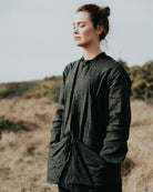 Woman wearing a black shirtstanding in a natural setting with trees and grass.