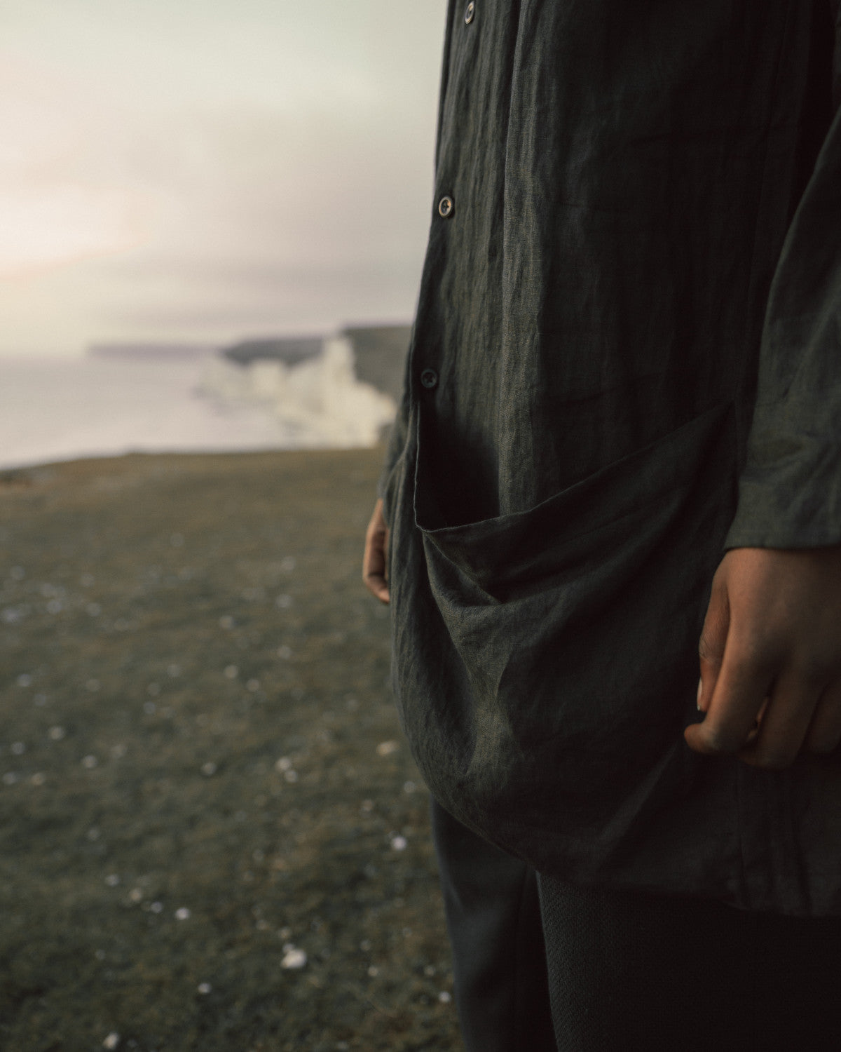 Person standing by a body of water with a scenic background